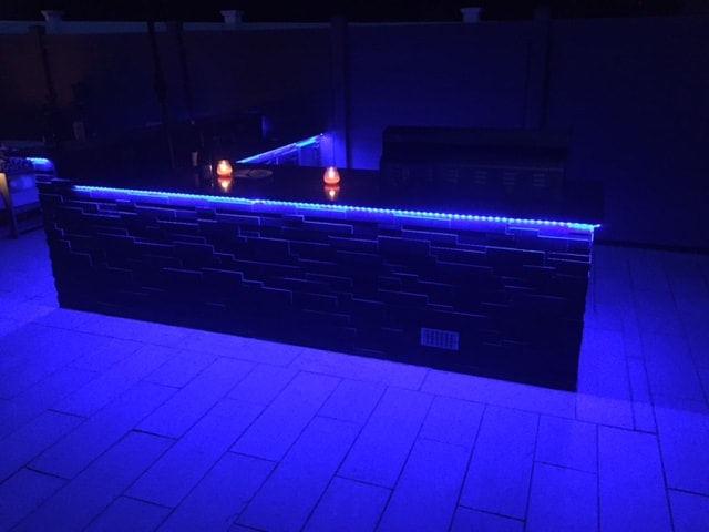 Norstone Aksent Modern Stone Cladding in Ebony Color on an Outdoor Kitchen with undermounted blue LED lighting